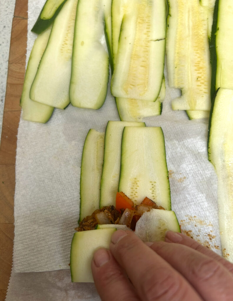 rolling up zucchini slices for enchilaadas
